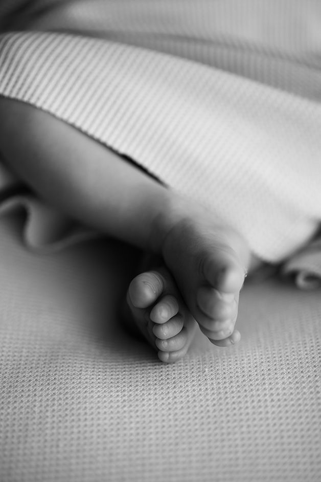 Close-up of tiny baby feet resting on textured white fabric.