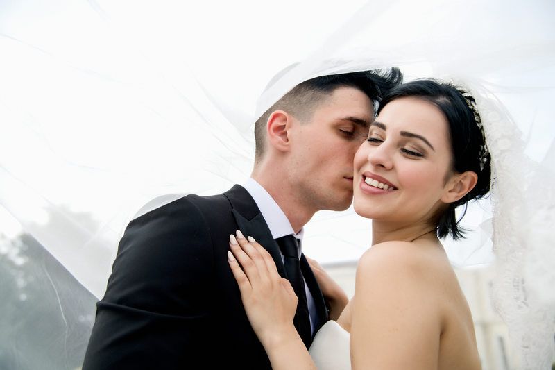A romantic wedding portrait captured outdoors with a tender moment between newlyweds.