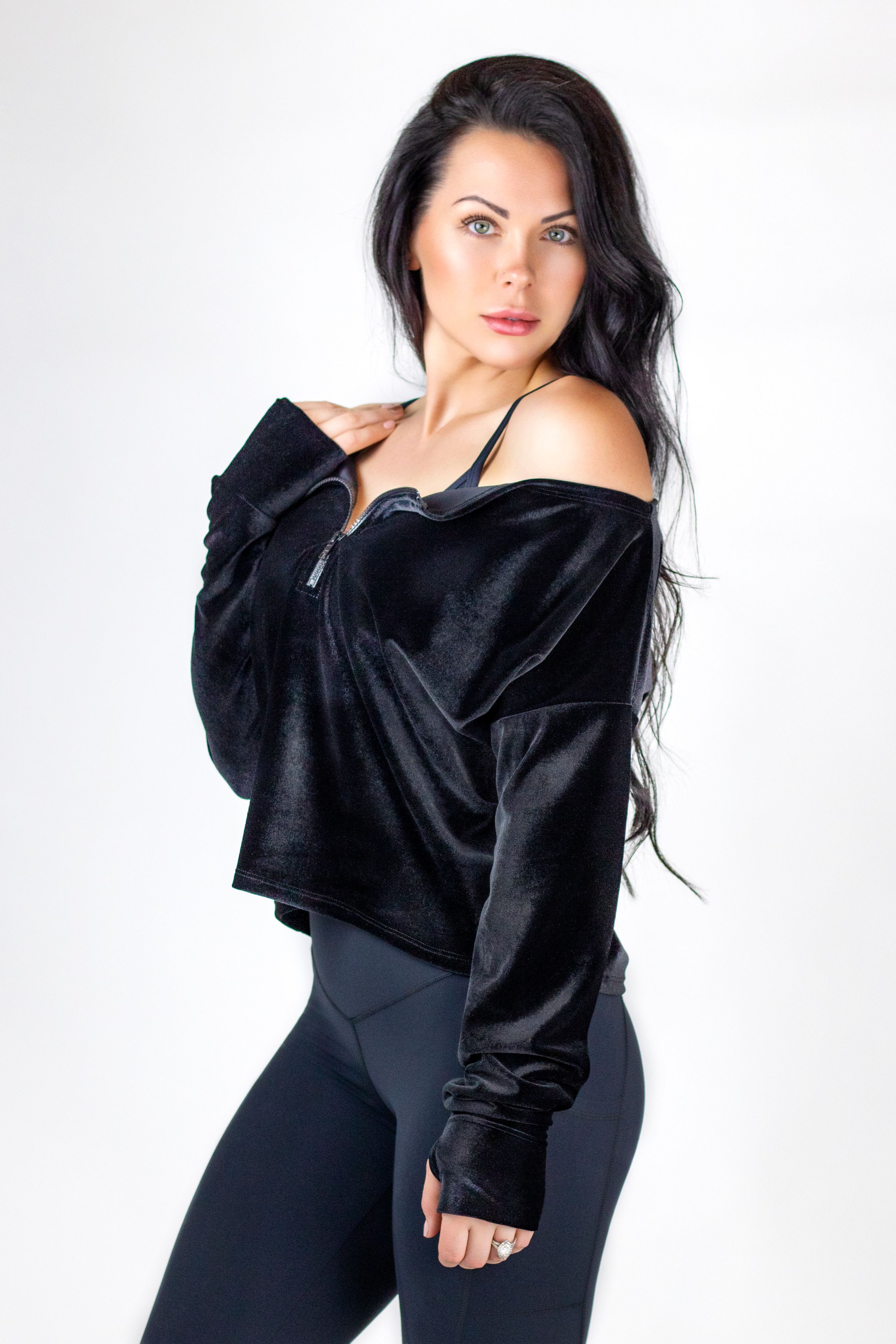 Fashion model in black outfit poses against white background in artistic photo series.