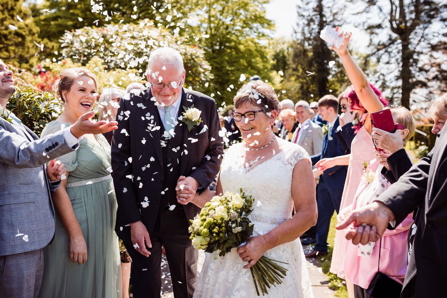 Wedding celebration with confetti being thrown in an outdoor garden setting.