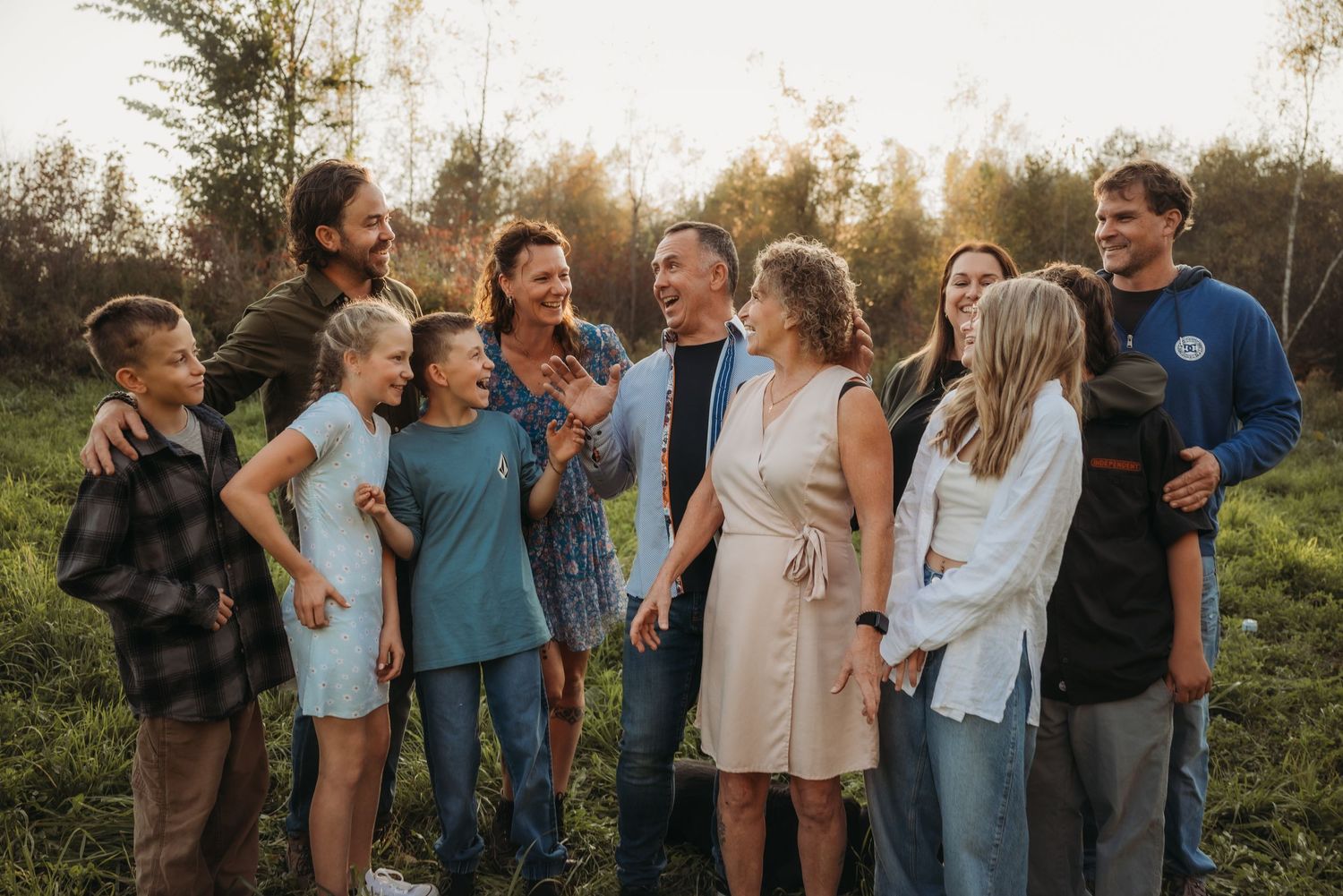 A group stands together outdoors sharing joyful laughter against a natural sunset backdrop.