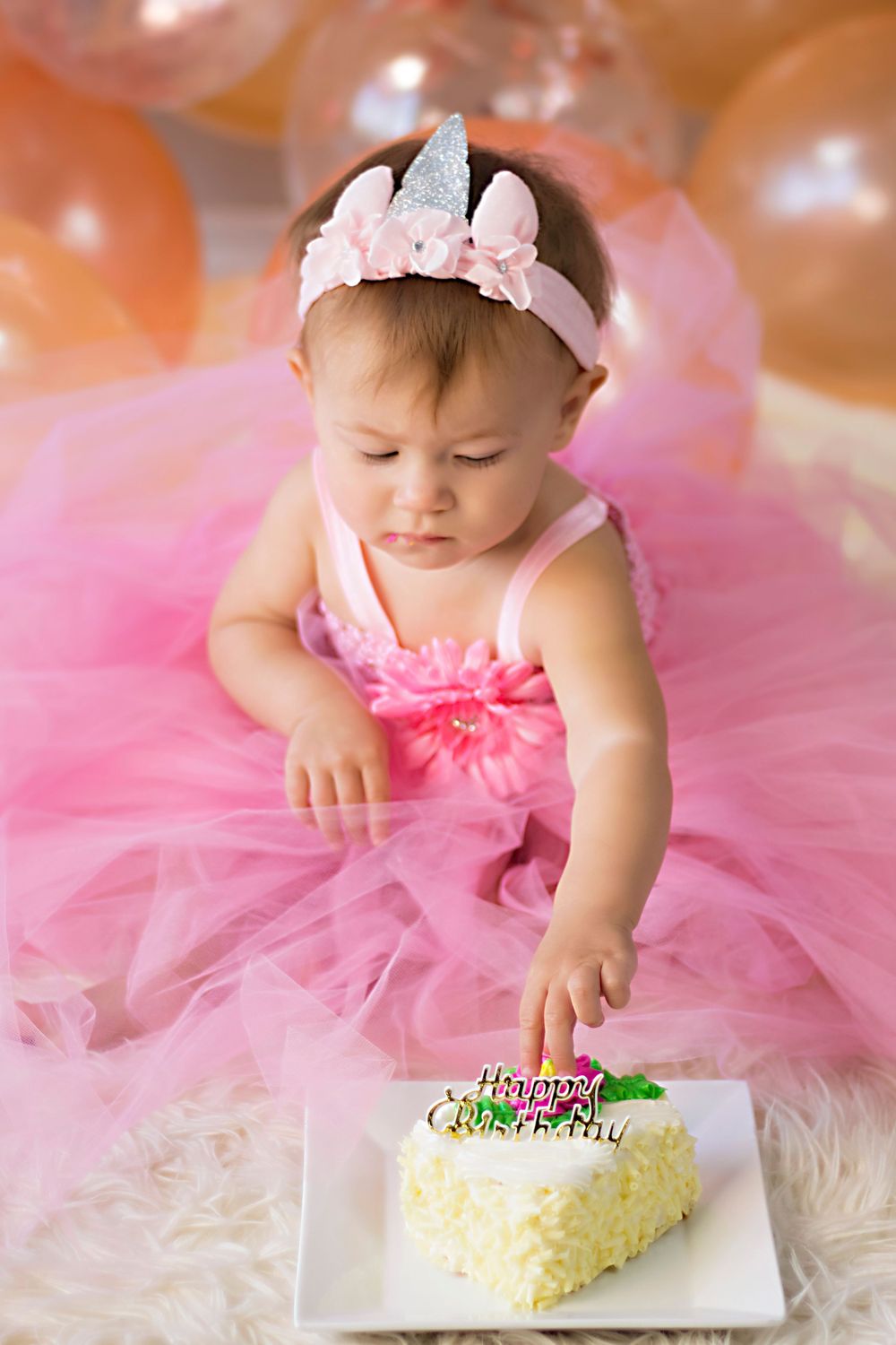 Small cake smash session with pink tulle dress and white frosted cake.