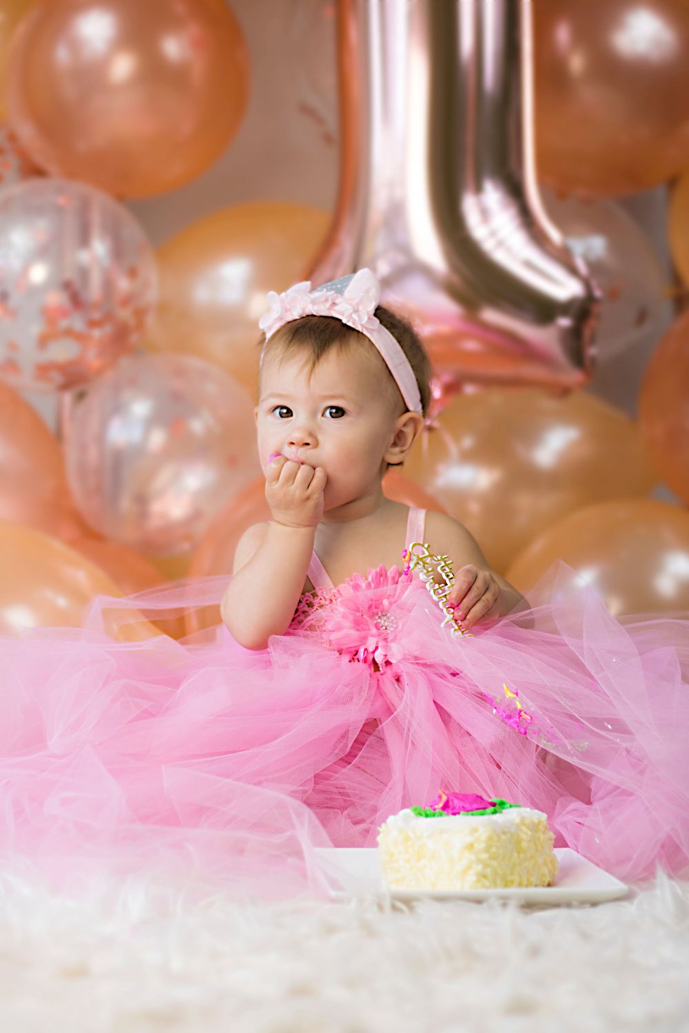 First birthday celebration setup with pink tulle dress and white cake.