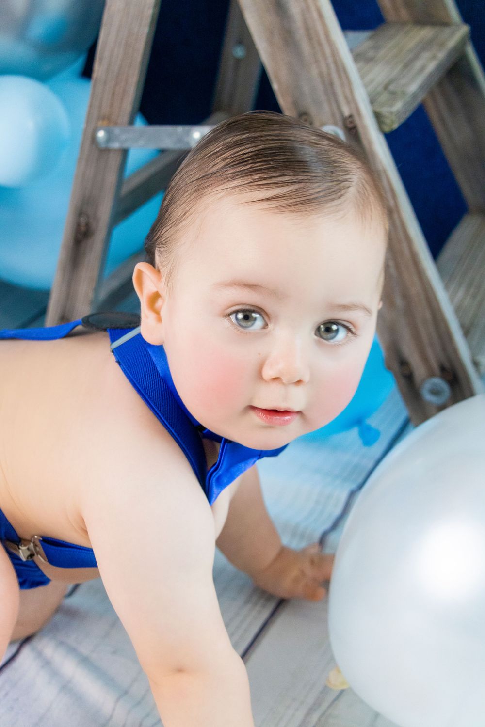 Blue themed birthday photo session with white and blue balloons.