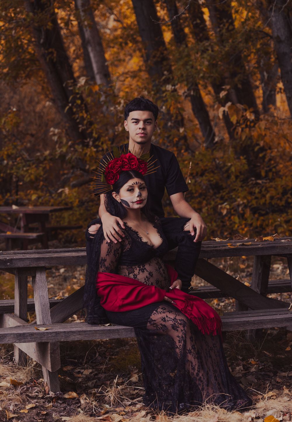 Autumn photoshoot on wooden bench with rustic fall colors in background.