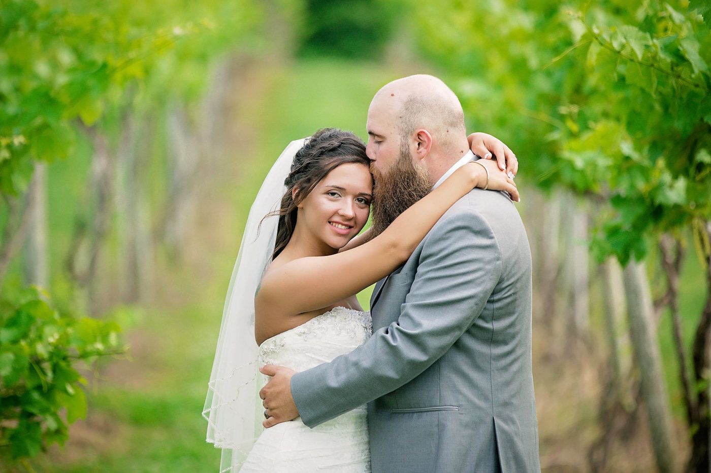 Wedding couple embraces in a lush vineyard setting during their special day.