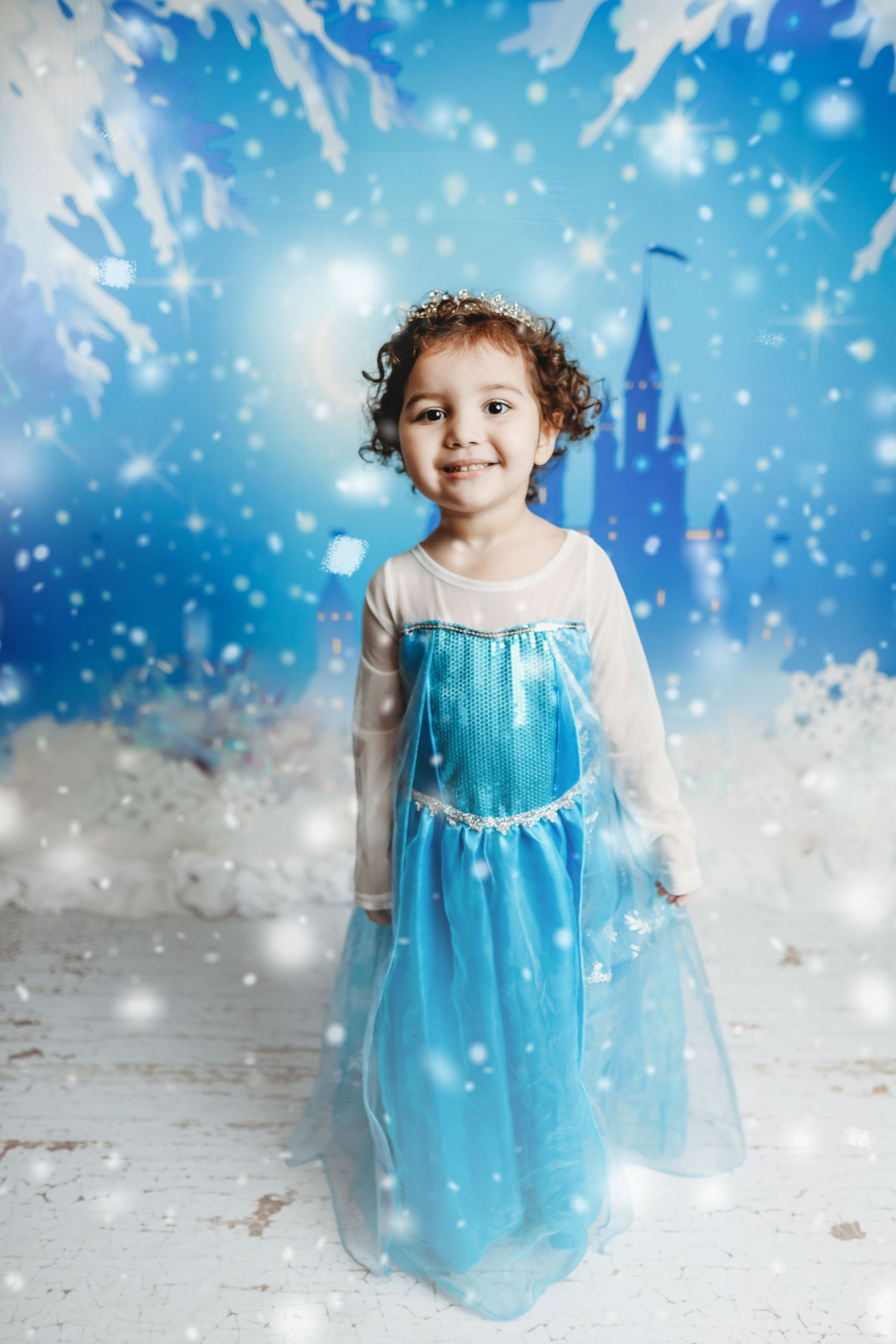 Magical winter scene with blue dress against snowy backdrop and castle silhouette.
