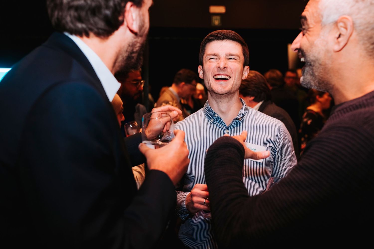 Three people enjoying a humorous moment together at what appears to be a social function.