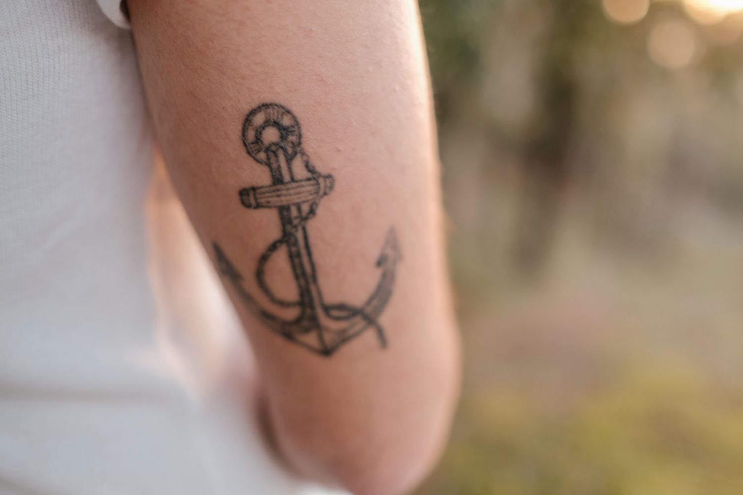 Close-up of an anchor tattoo design on someone's arm with bokeh background.
