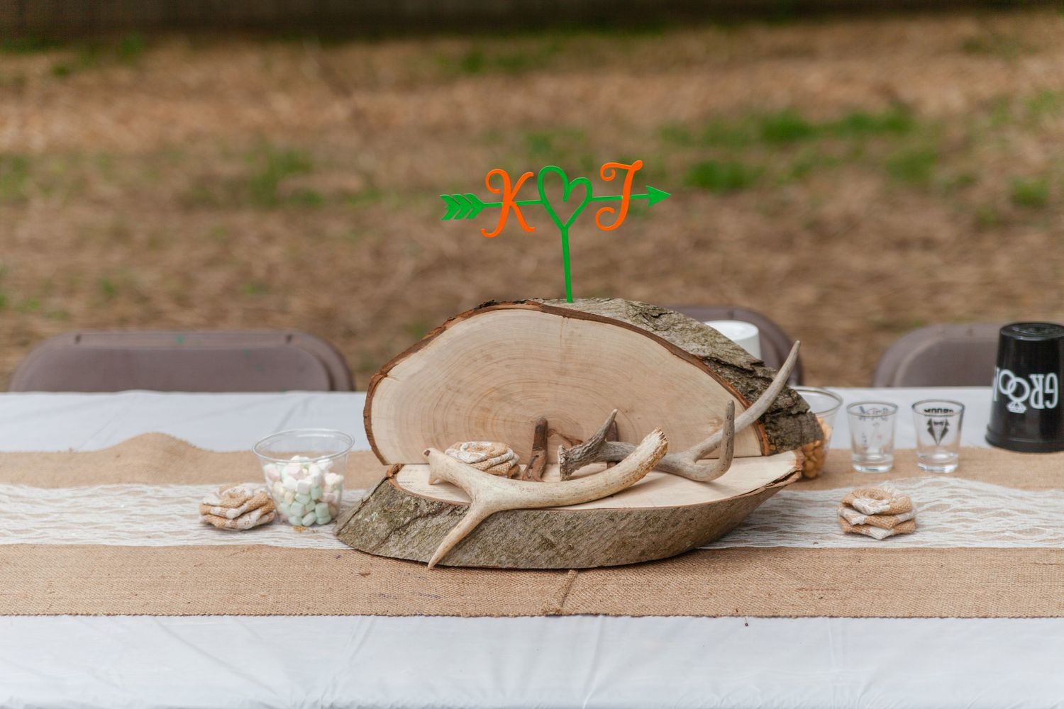 Long banquet table decorated with natural elements and mason jars for outdoor event.