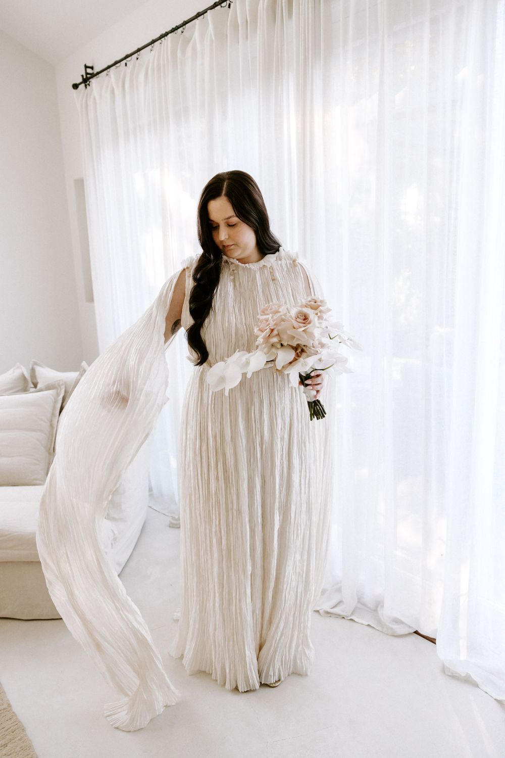 Flowing white pleated gown with intricate details captured in natural light.