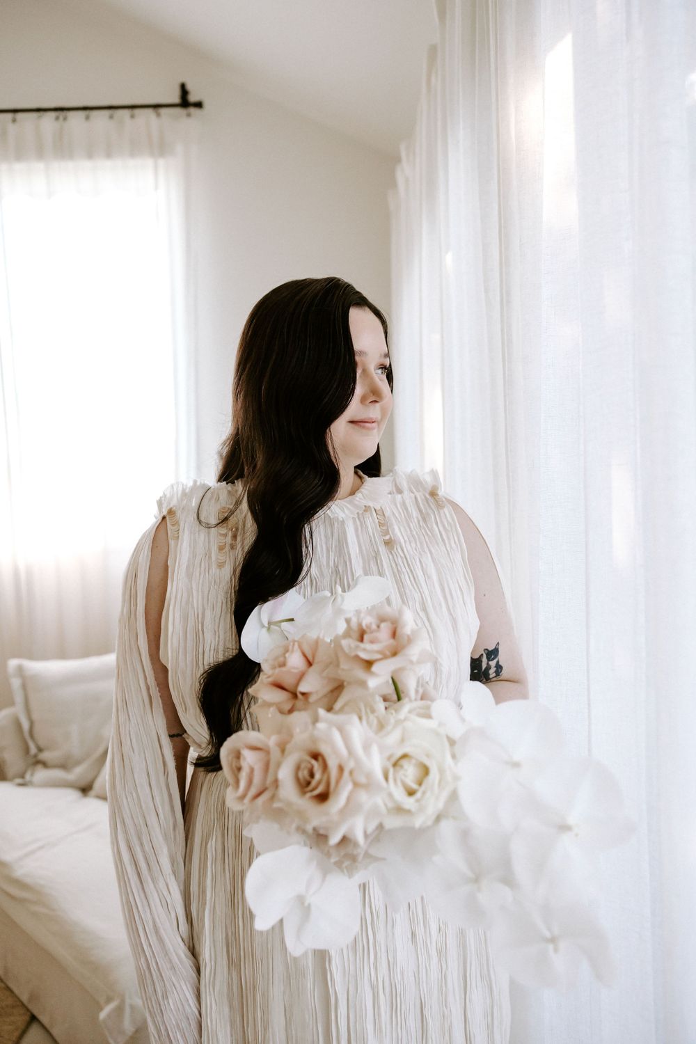 Soft portrait with white roses and flowing dress by window light.