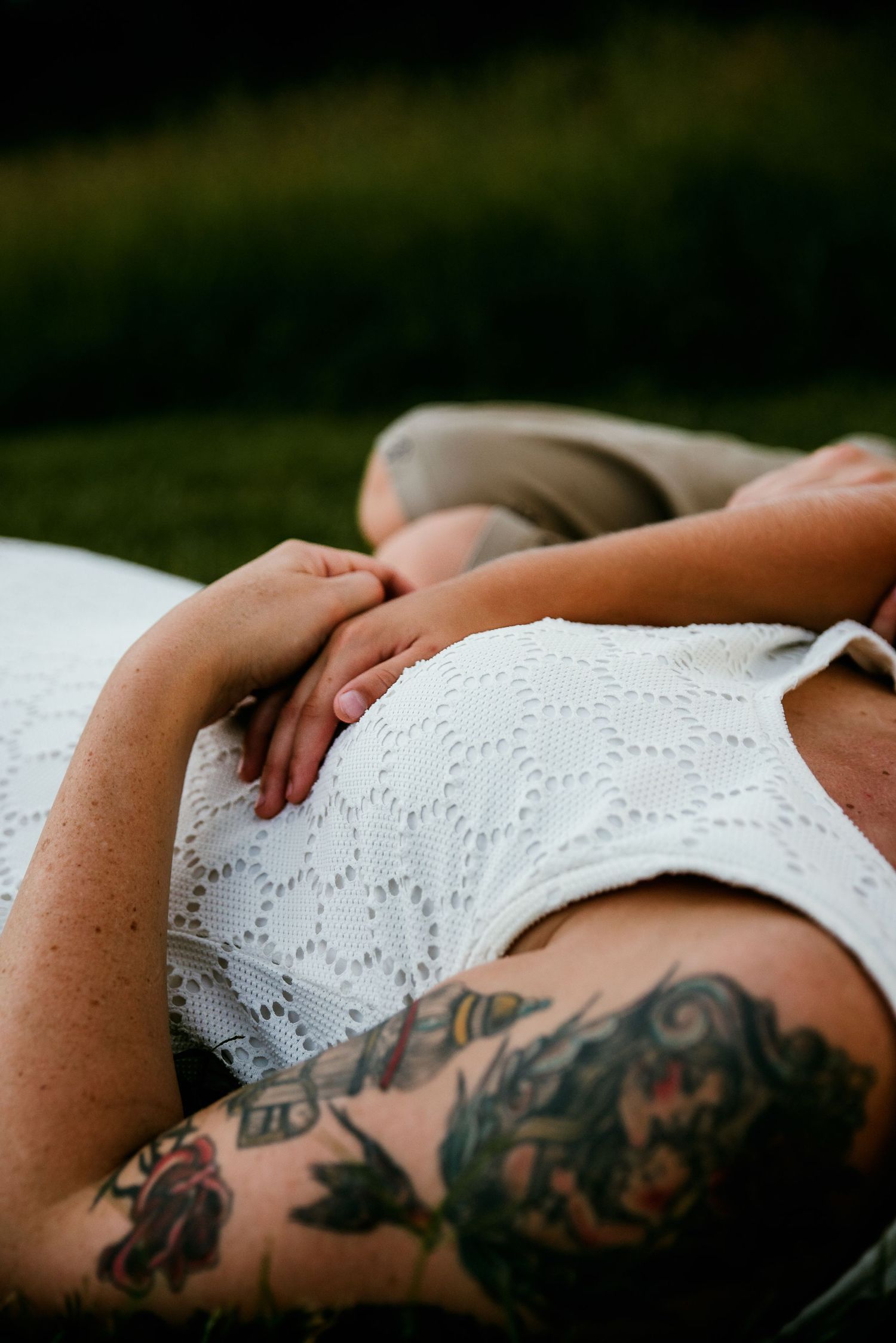 Mother and son holding hands lying down in a field.