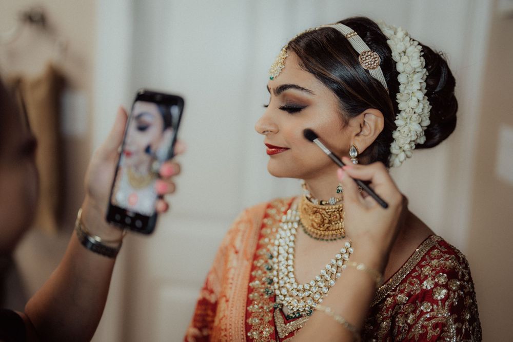 Behind the scenes of bridal makeup preparation with phone camera and traditional Indian wedding attire.