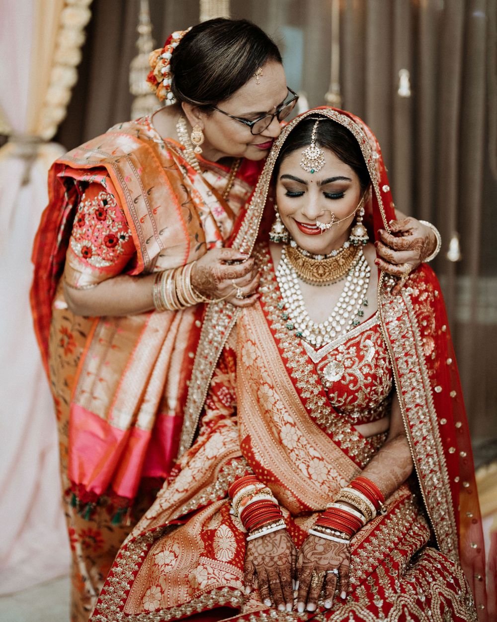 Intimate moment during Indian wedding preparations as final adjustments are made to bridal attire.