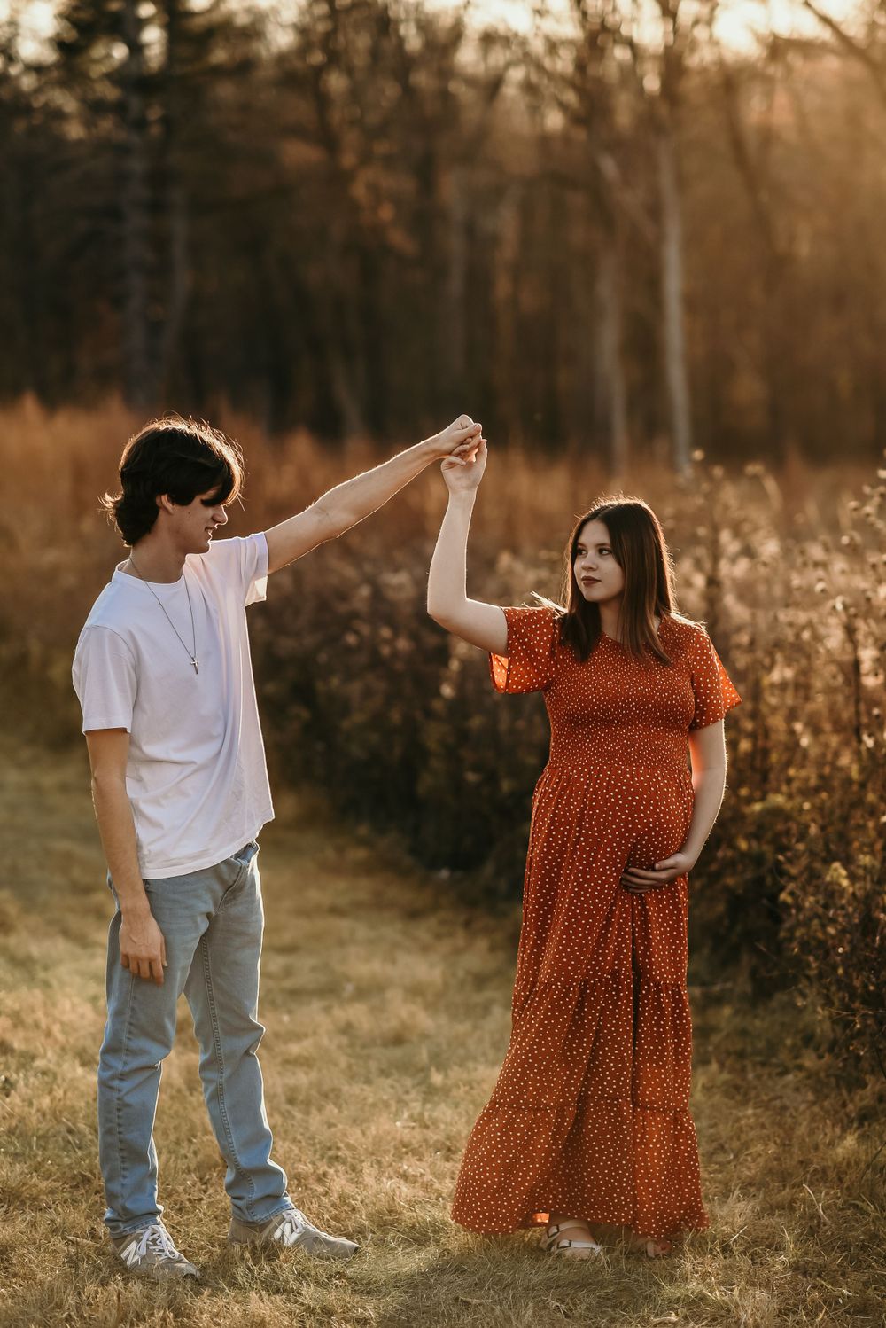 Couple dancing together in a field during golden sunset hour.