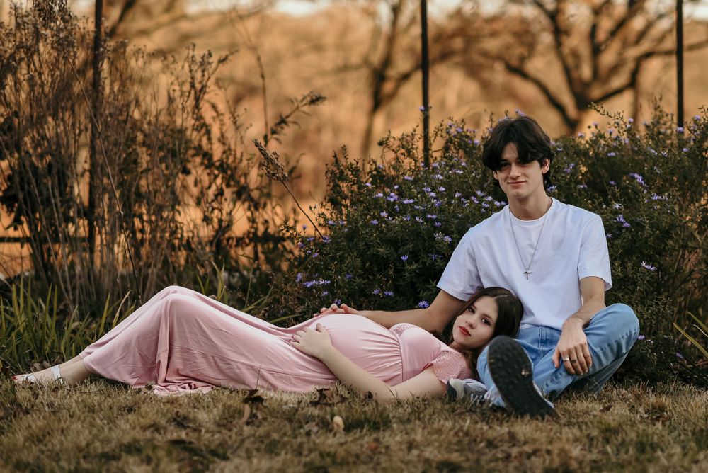 Couple relaxing together on grass during golden hour sunset.