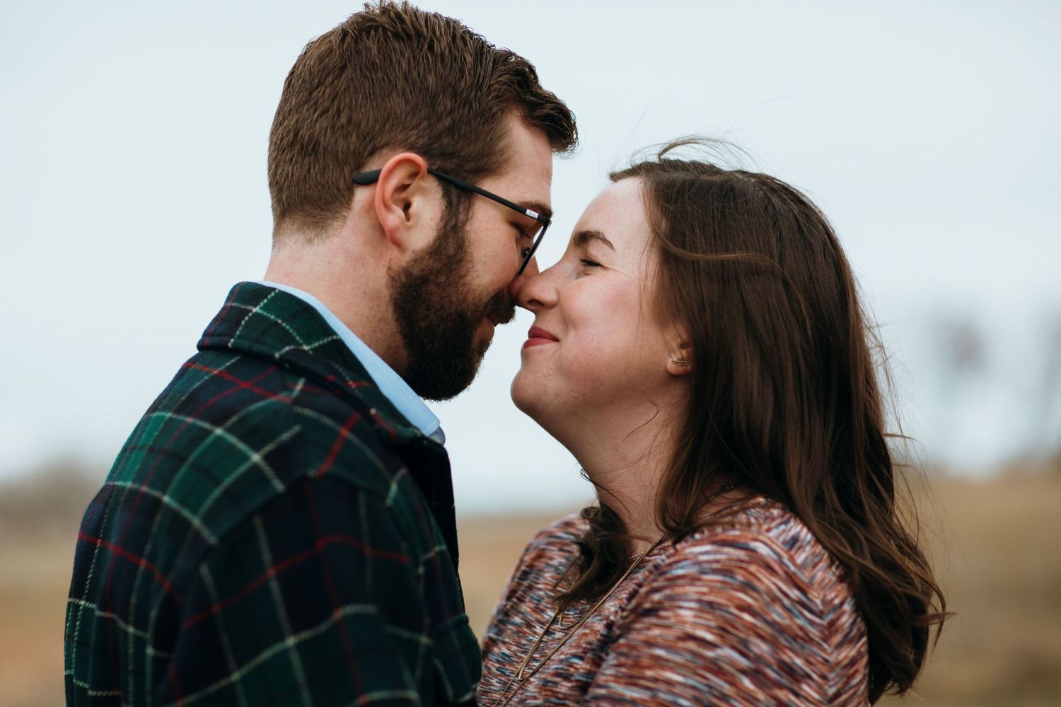 Closeup of girl and boy touching noses while wind is blowing girls hair