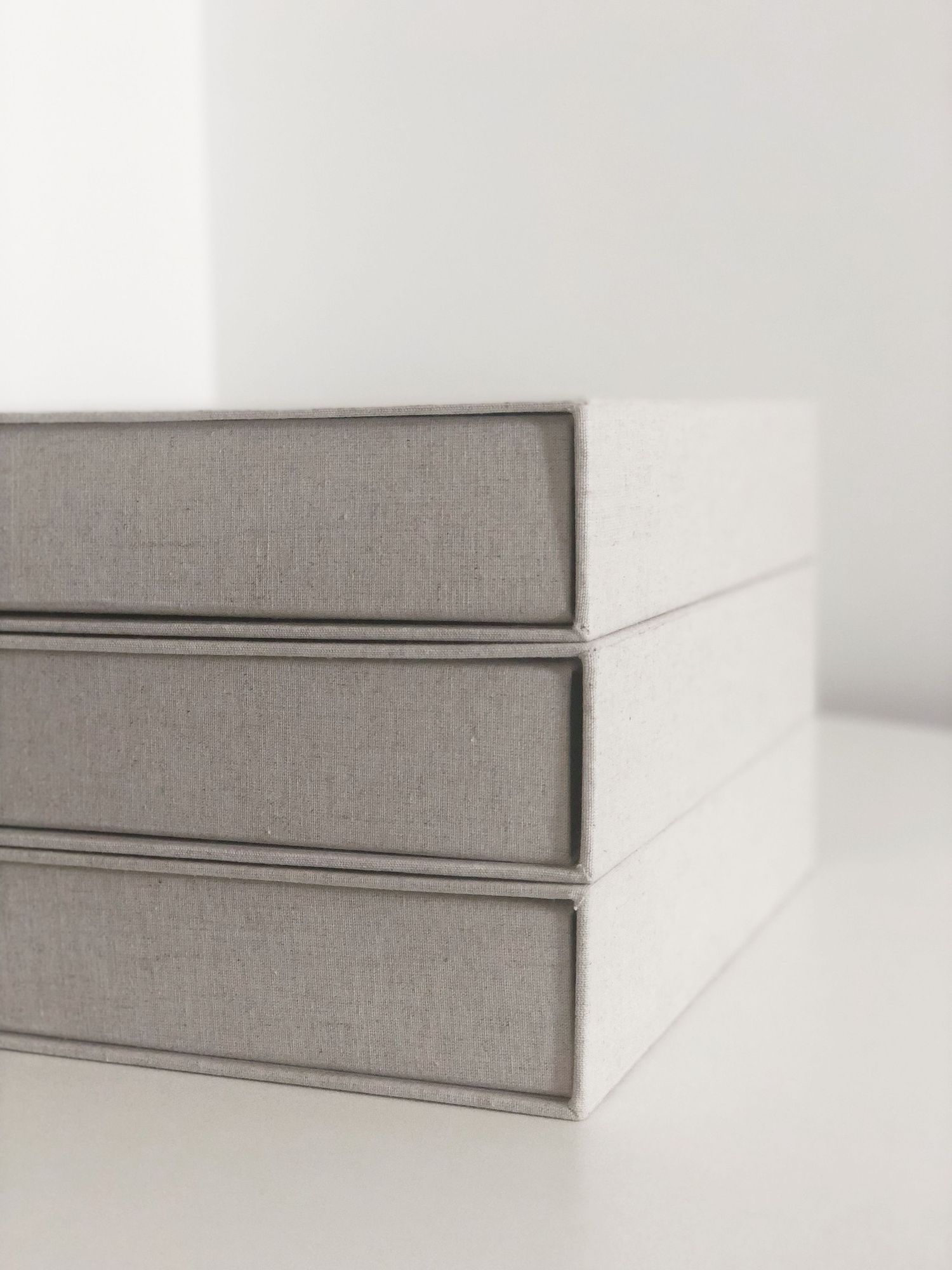 Elegant grey linen photo albums stacked with clean minimalist design.