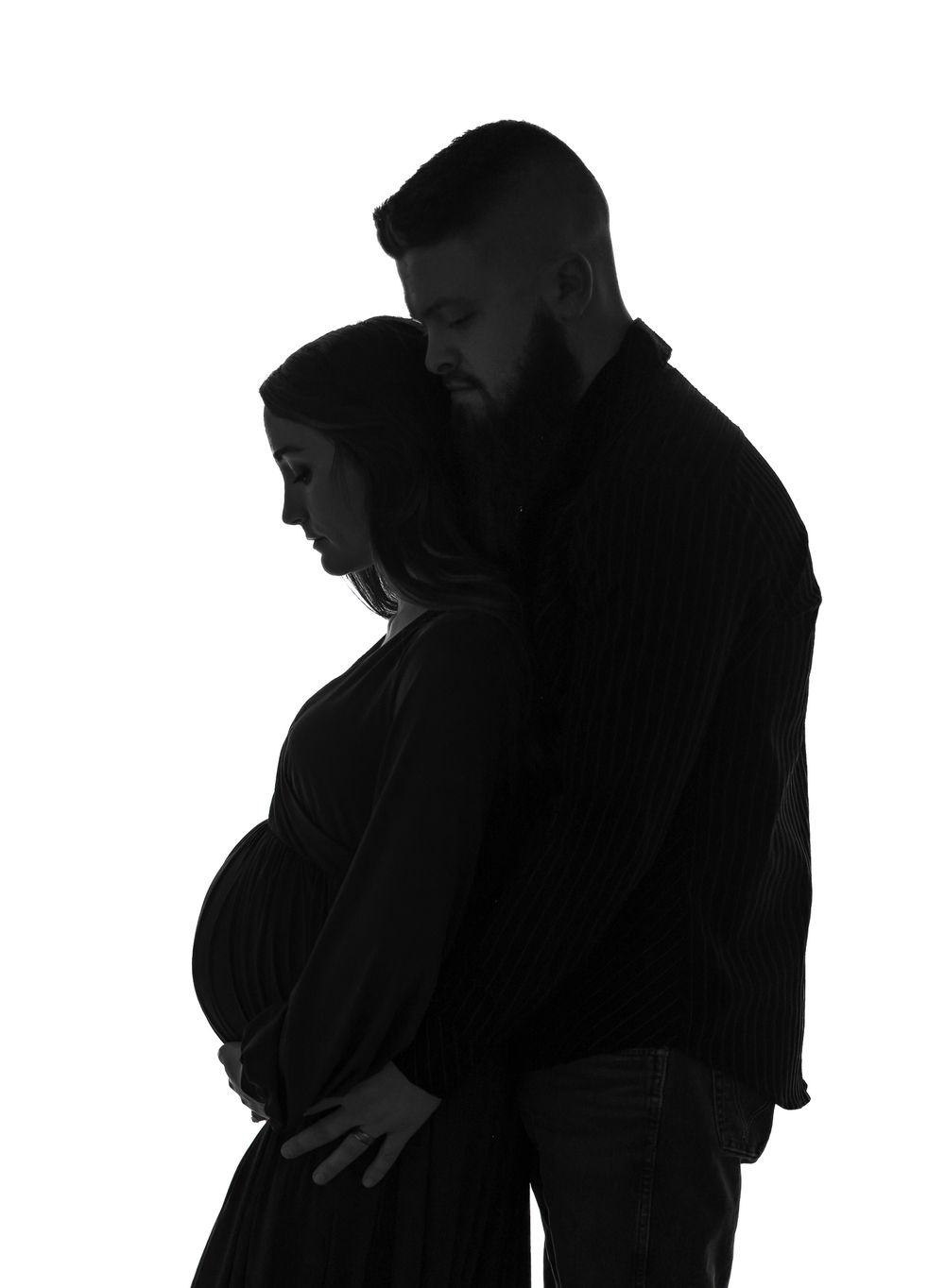 Artistic silhouette of an expecting couple embracing against white background.