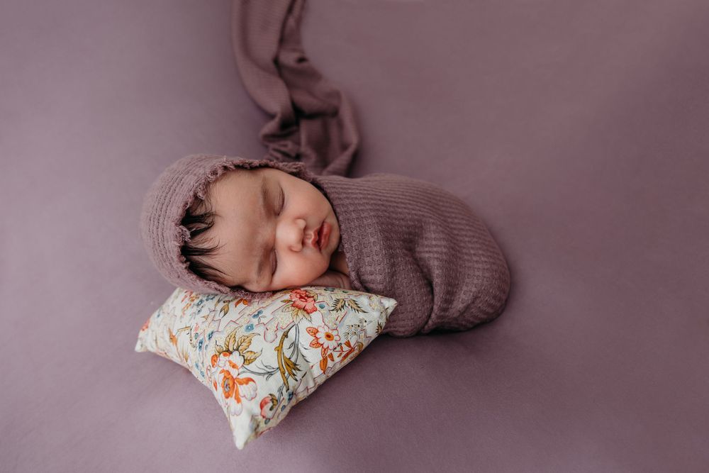 newborn posed table top wrapped purple western new York photographer trained professions skilled local east aurora NY