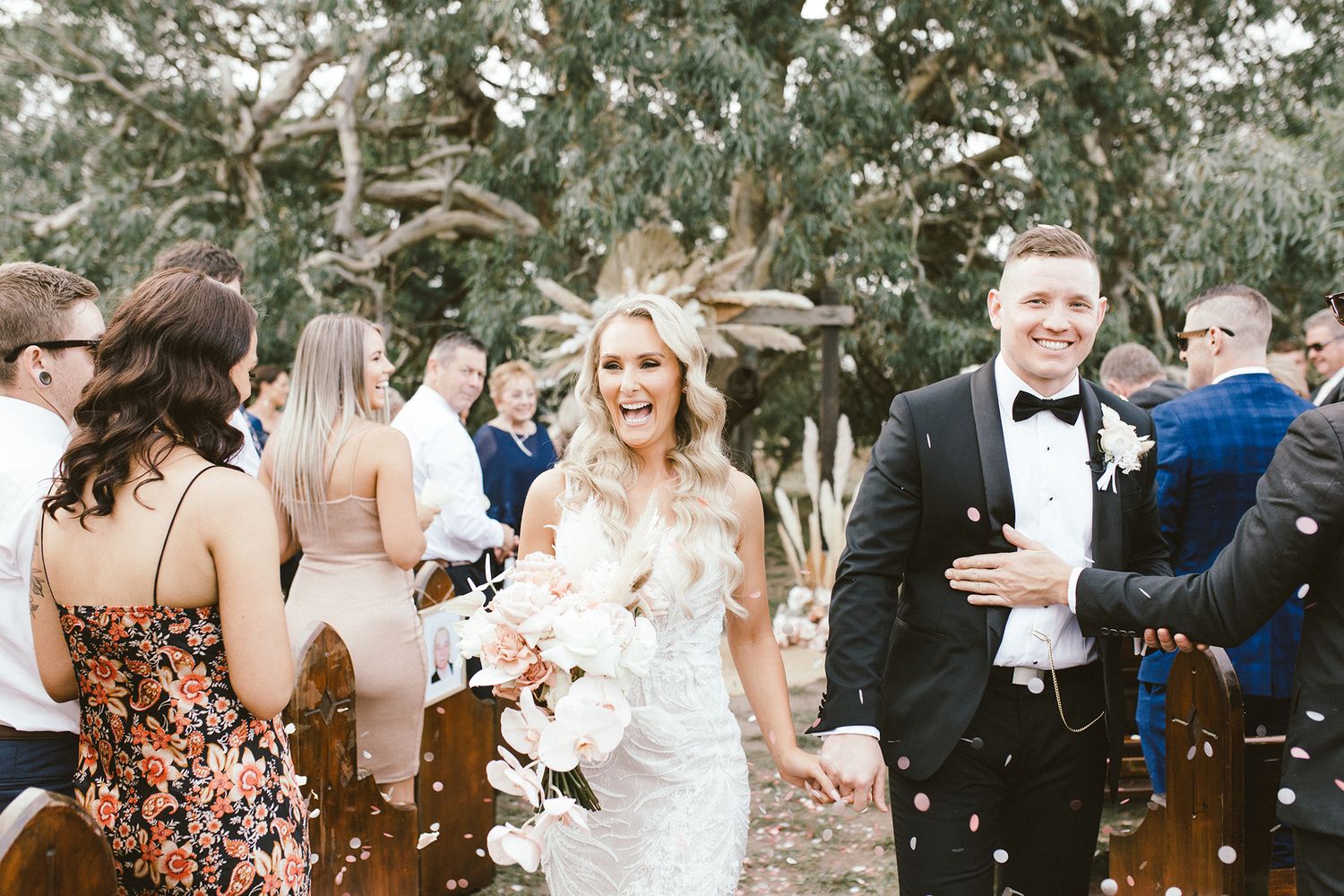Joyful wedding celebration with guests tossing petals in outdoor garden setting.