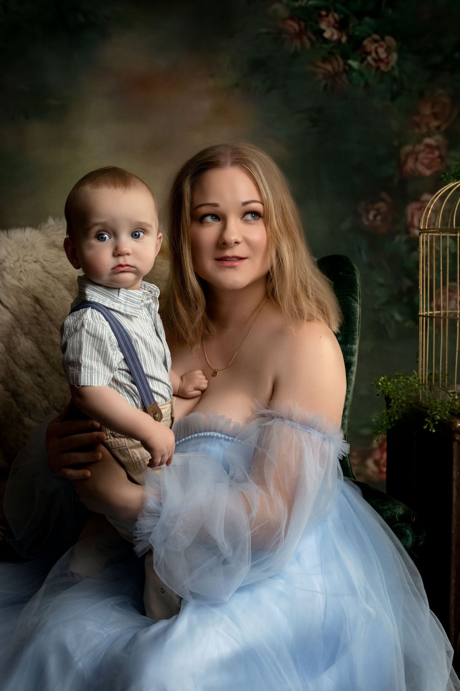 A dreamy portrait in soft blue tones featuring an ethereal tulle dress against a moody dark backdrop with roses.