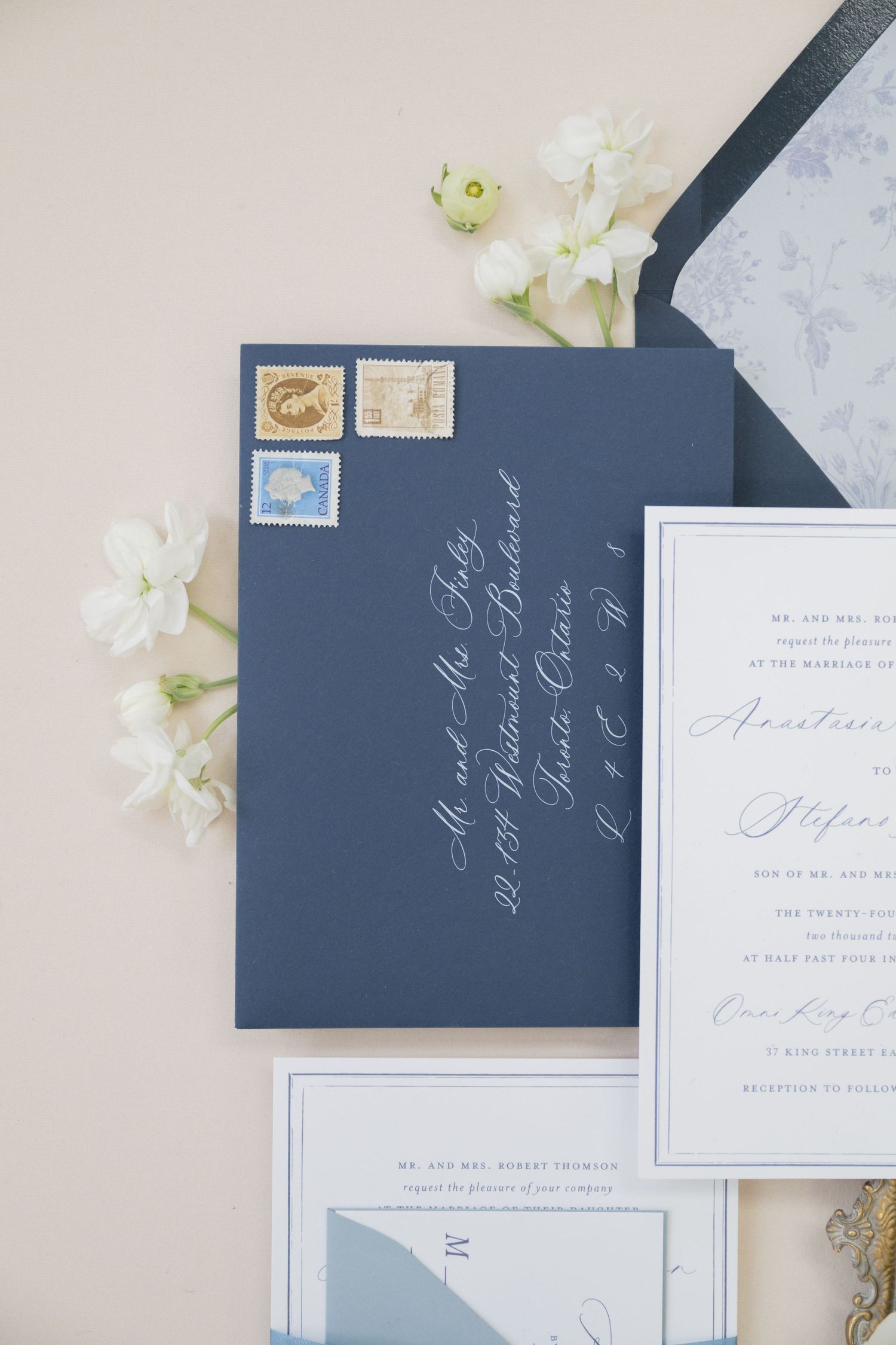 Navy blue envelope with vintage stamps and white calligraphy for wedding invitation.