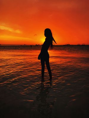 Dramatic beach silhouette of woman at golden hour, with vivid orange sunset—photographed by Michelle Baum Photography