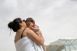 Mother hugging child with overcast sky photo captured by Michelle Baum Photography