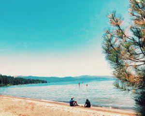 Two people sitting by blue waters in Lake Tahoe, CA. 2017 Captured by Michelle Baum Photography