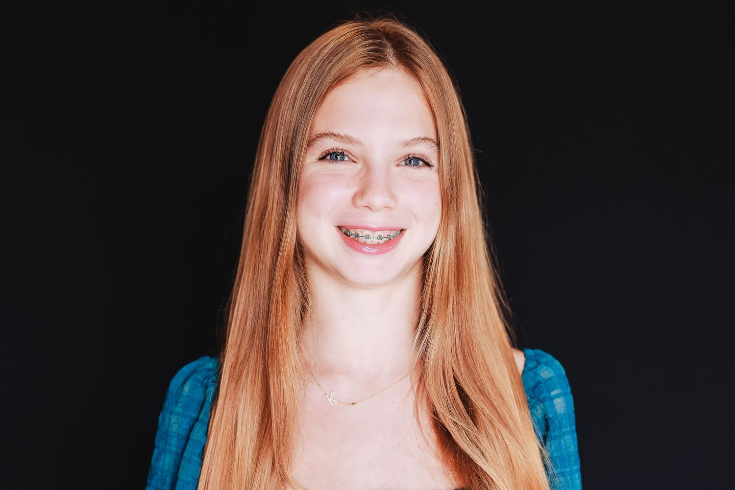 Portrait of a smiling youth with long straight red hair wearing blue.