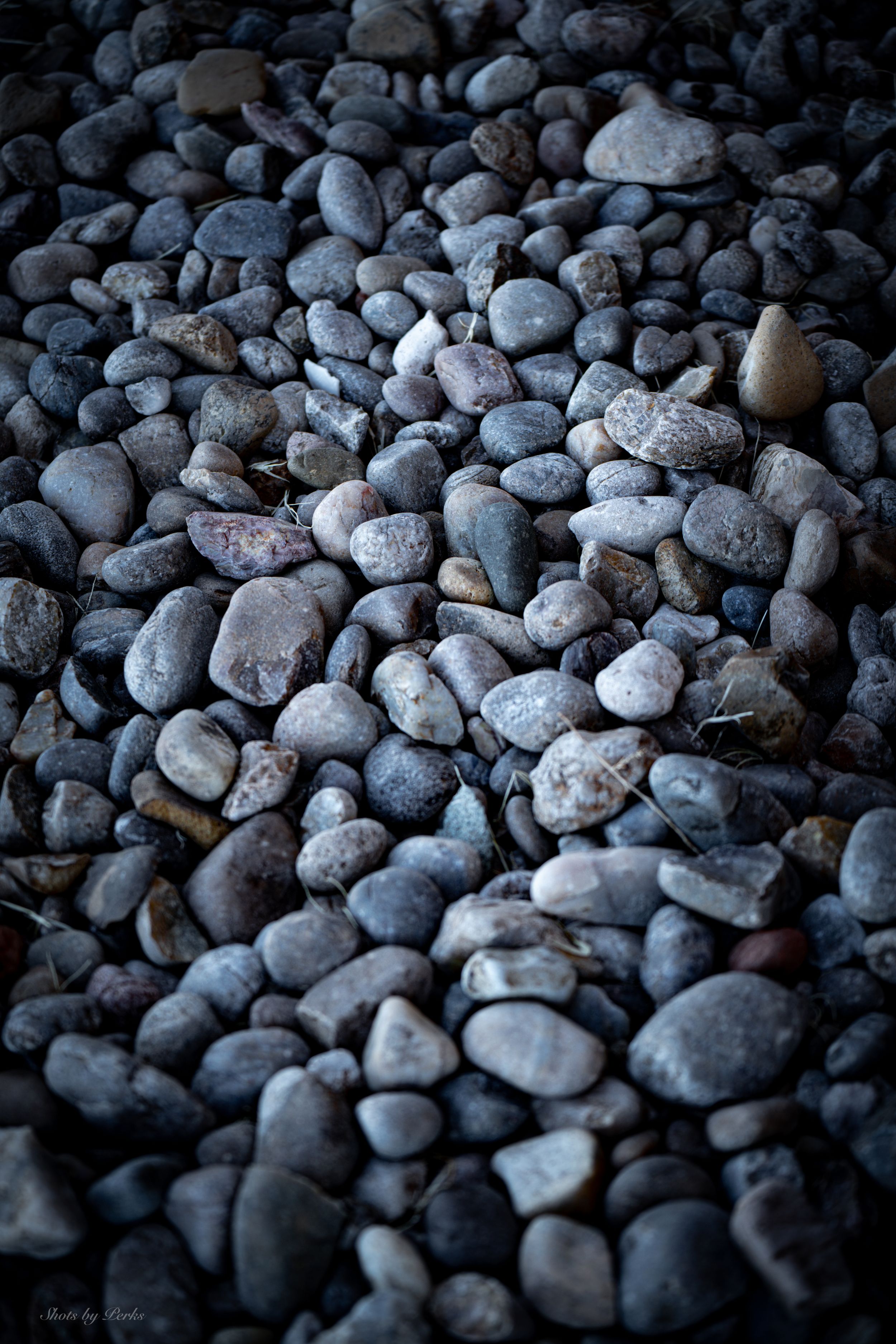 Close-up of smooth river rocks and pebbles in various shades of grey creating a natural pattern.