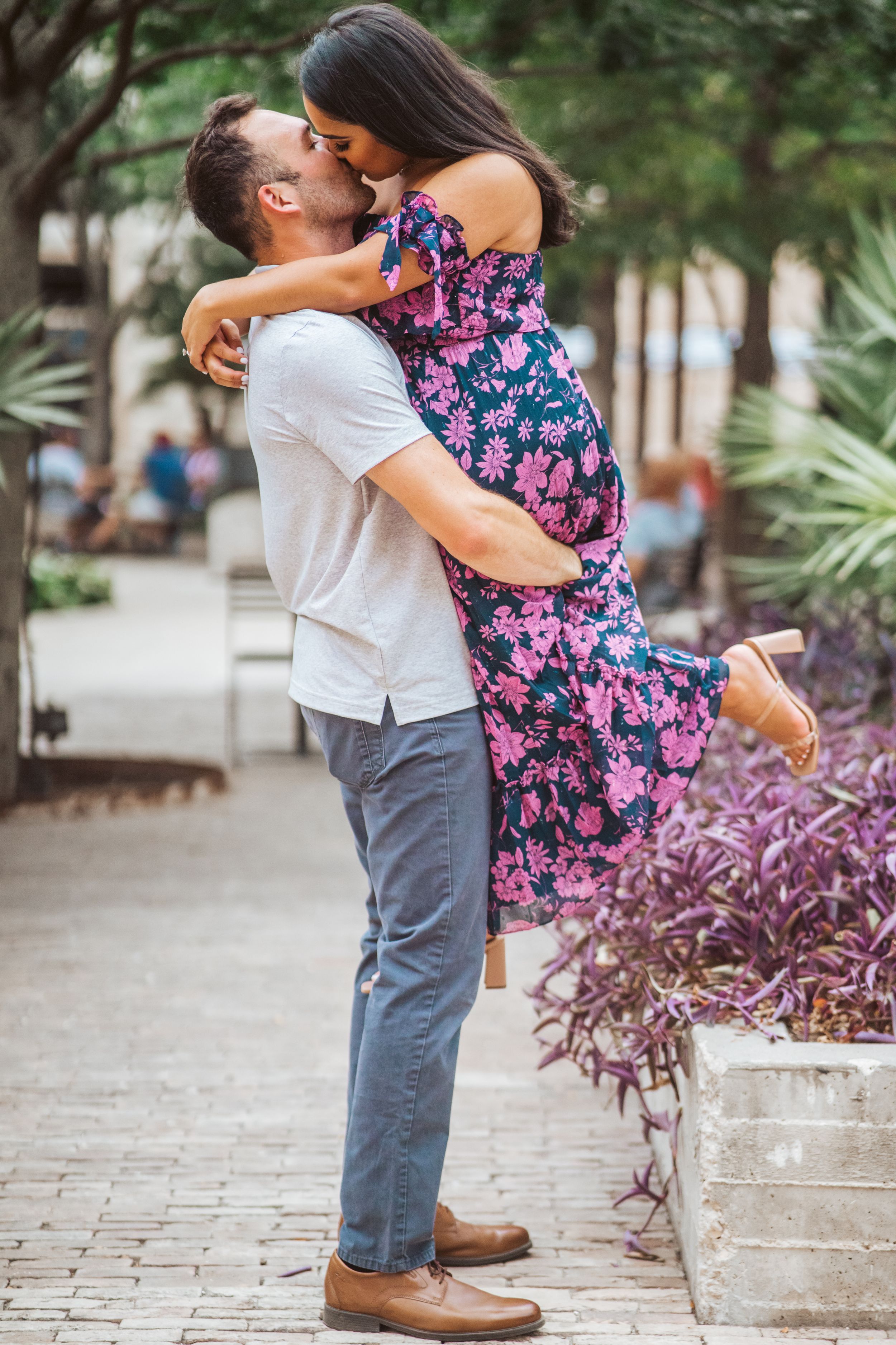 Romantic couple embracing outdoors in front of tropical plants.