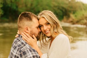 An intimate portrait of a couple embracing by the water's edge during golden hour.