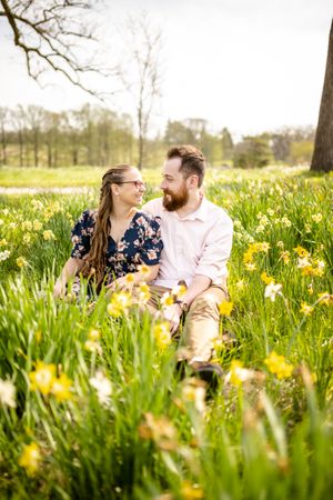 Couple laughing together while sitting among blooming spring daffodils.