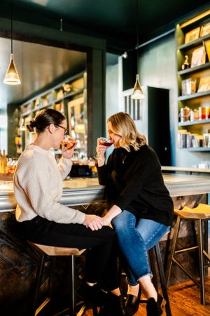 Two people enjoying drinks and conversation at a cozy bar with warm lighting and wooden decor.