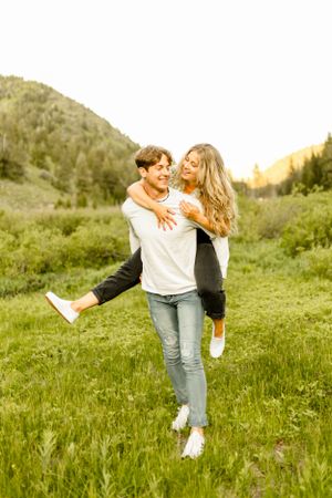Couple playing and dancing together in a sunlit mountain meadow.