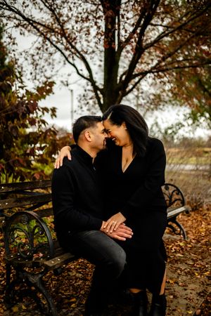 Couple sharing intimate moments on bench surrounded by autumn foliage.
