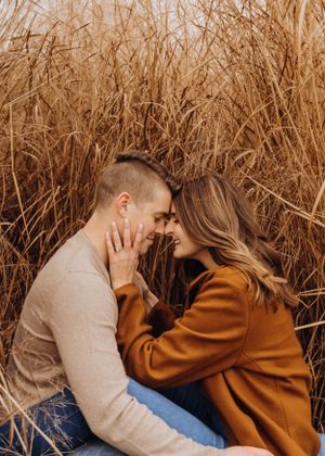 A couple embracing in a field of tall golden autumn grass during sunset.