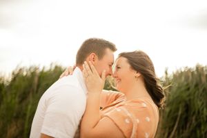 Couple shares tender moment in tall grass during golden hour.