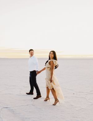 Dancing couple spins gracefully across white salt flats at sunset.
