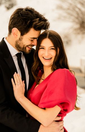 A couple in formal attire sharing intimate moments against a snowy winter backdrop.