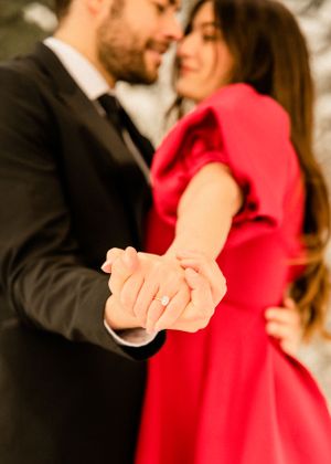 Close-up sequence of a couple holding hands with red dress detail against snowy backdrop.