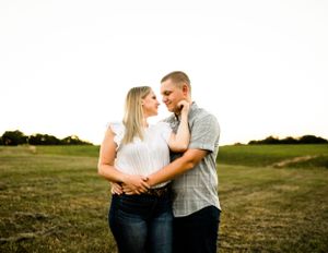 A couple shares an intimate moment in an open field at golden hour.