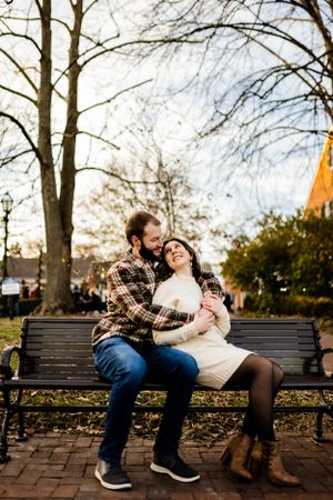 Romantic sequence on park bench during autumn with bare trees in background.