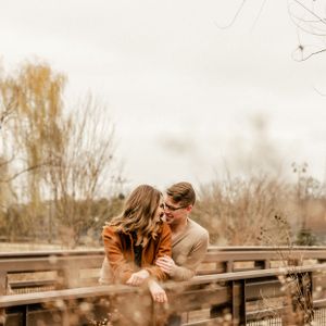 A couple sharing an intimate moment on a rustic wooden bridge.