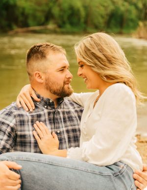 A romantic moment captured between a couple sitting close together by a serene waterfront.