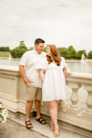 Couple in matching white outfits sharing intimate moments along stone balustrade.