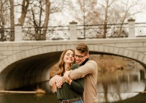 A romantic couple's portrait session under a stone bridge during sunset.